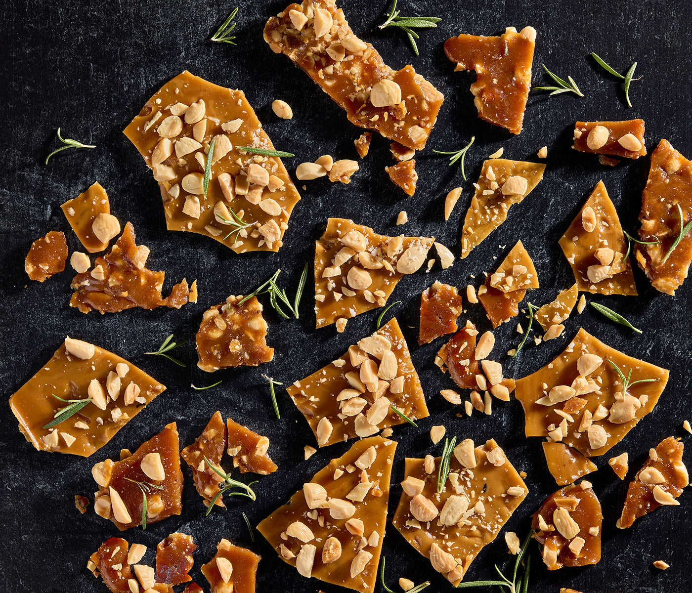 Toffee pieces with marcona almond scattered on a dark serving platter