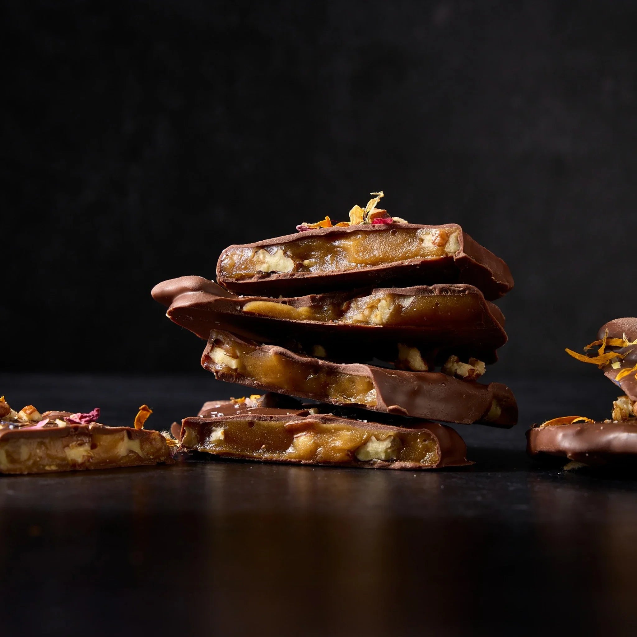 Toffee pieces with marcona almond scattered on a dark serving platter