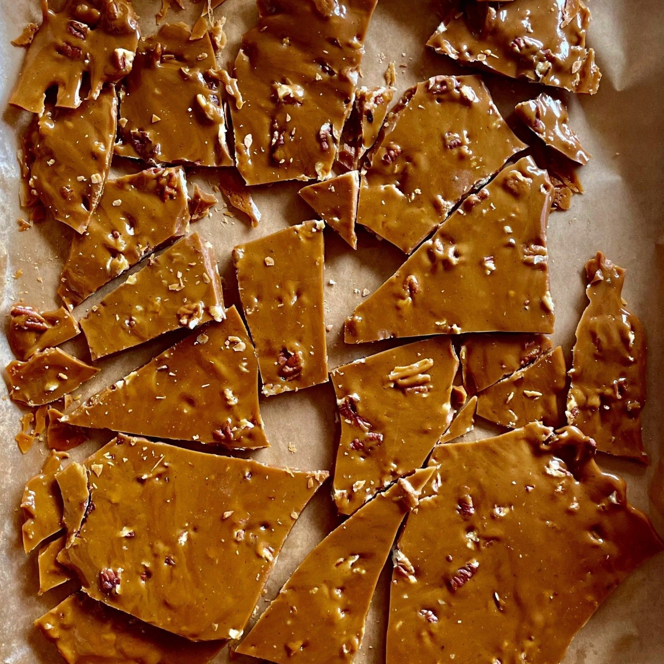 Milk Chocolate Toffee with pecans broken up into pieces to eat on a platter