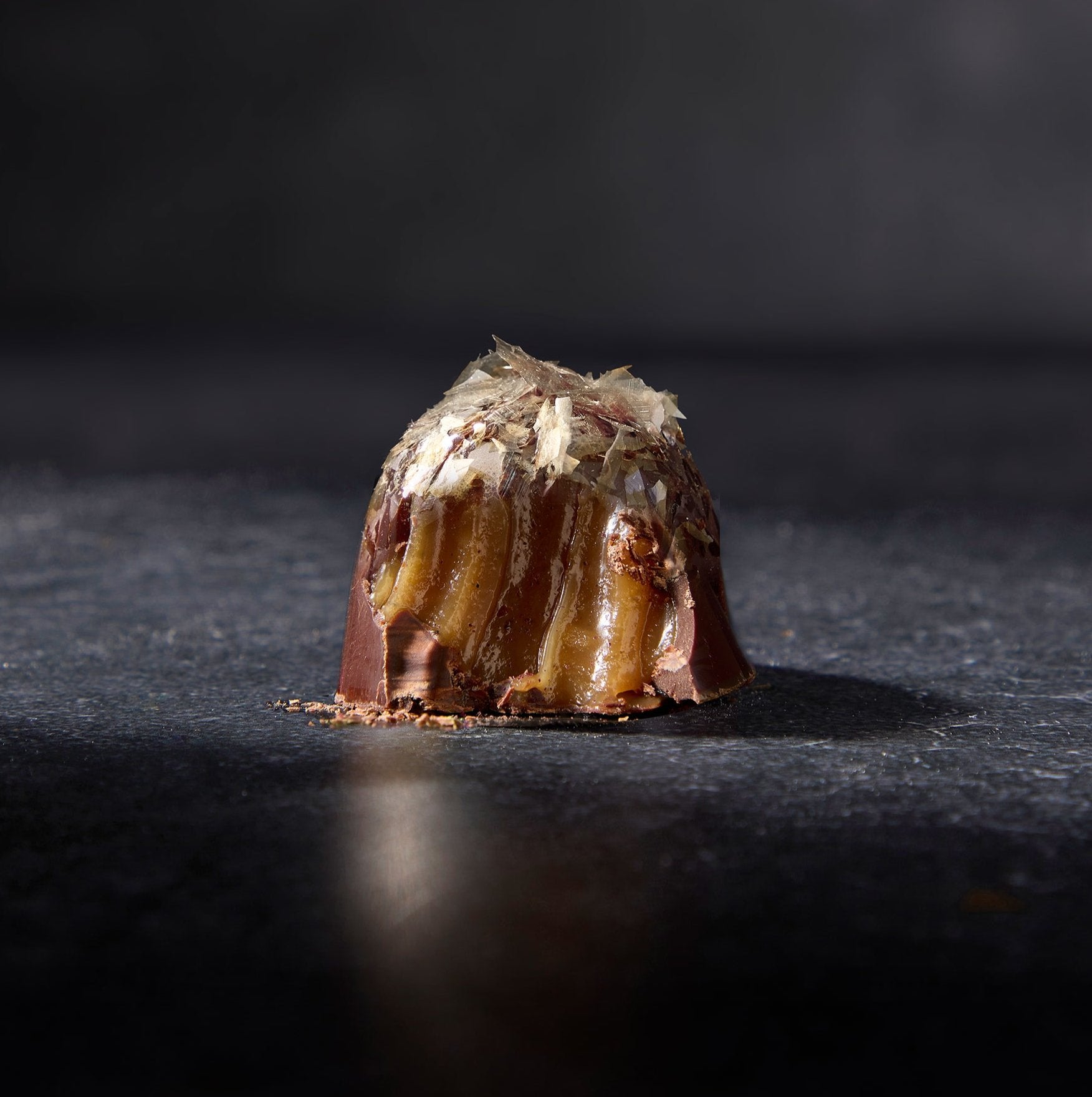 Lion's Mane Chocolate Truffle with one bite to reveal the hazelnut paste inside. Topped with Lion’s Mane gold.