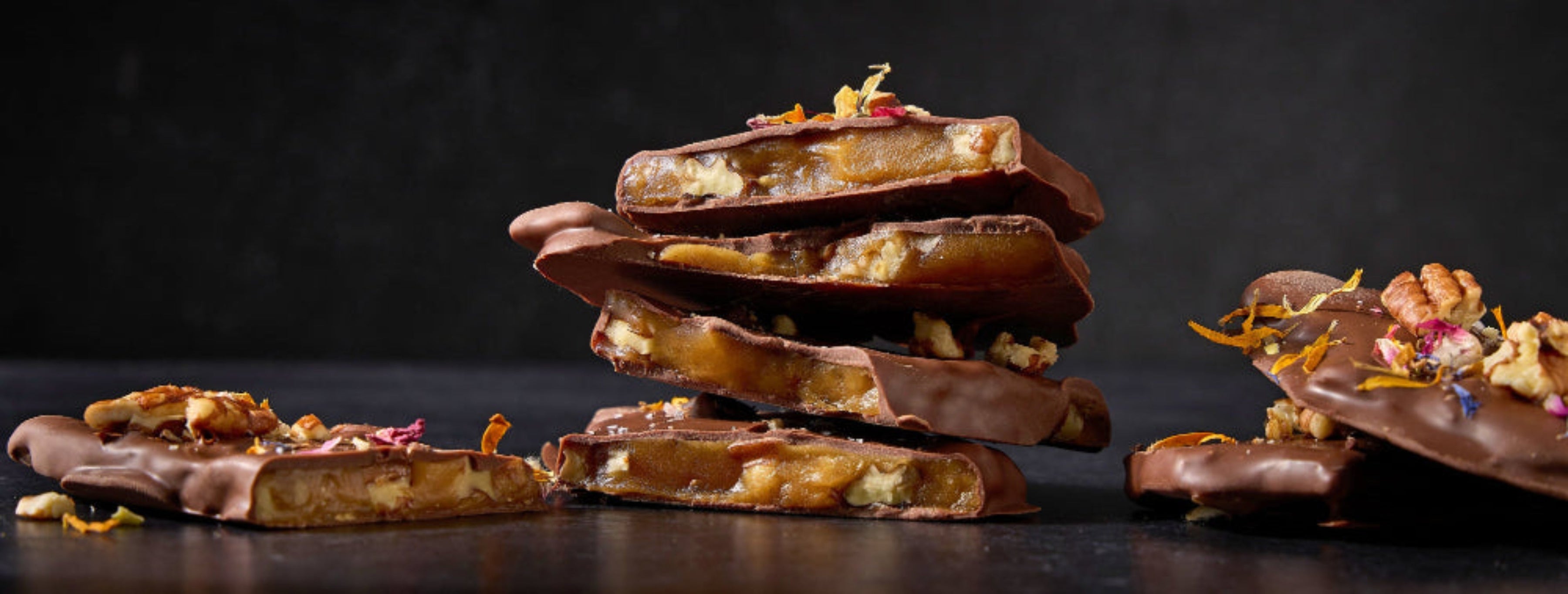 Stacked chocolate treats with floral elements on a dark background