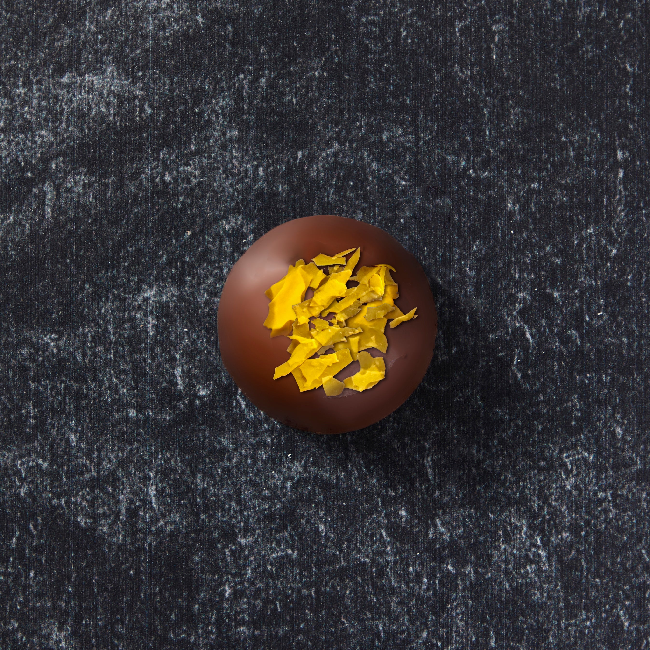 Milk Chocolate Truffle sprinkled with freshly grated turmeric in caramelized dark milk chocolate.