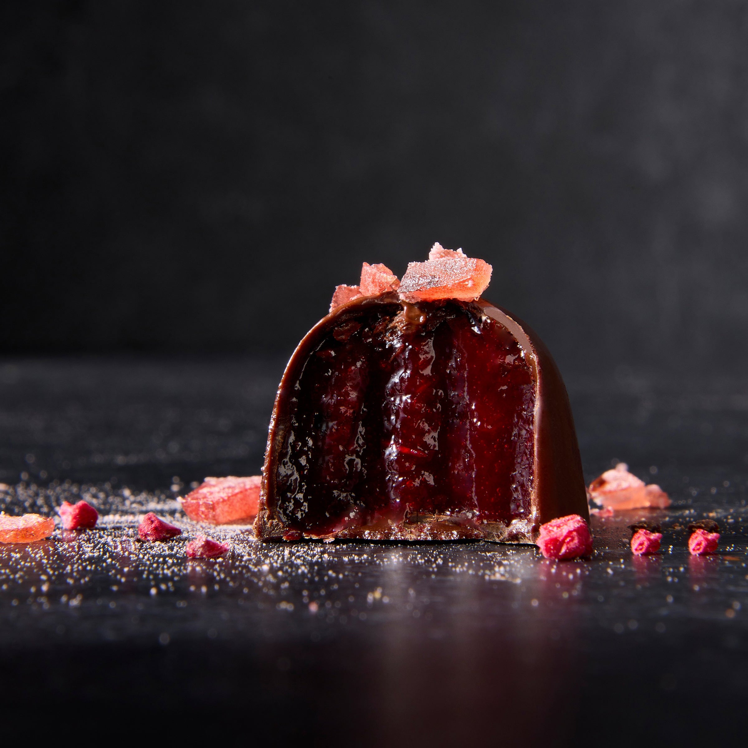 Dark Chocolate Truffle with bite taken revealing Hauts-de-France Raspberries + Sea Buckthorn Berry + Egyptian Geranium