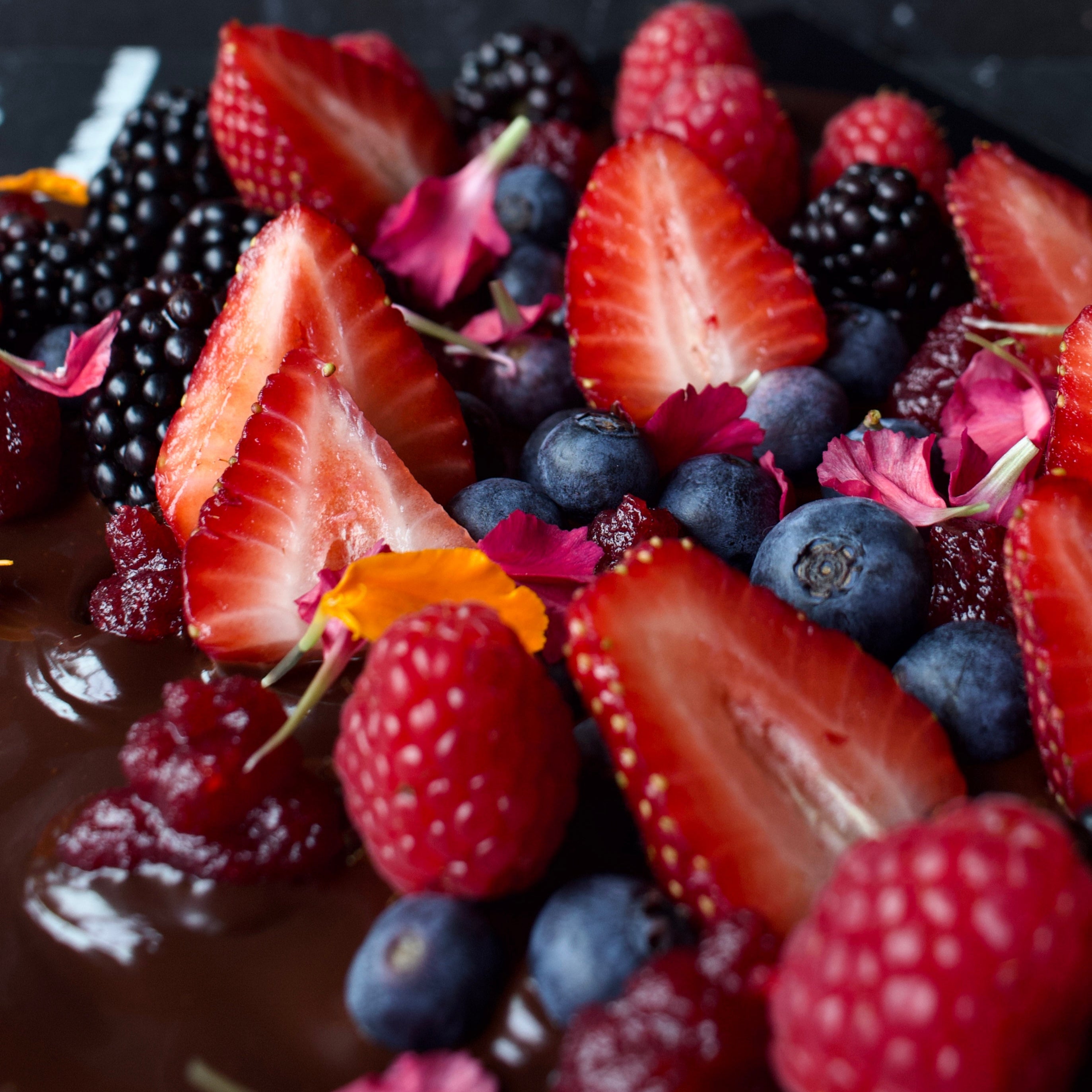 Beautiful closeup of Dark Chocolate topped with fresh strawberries, blueberries, blackberries and raspberries
