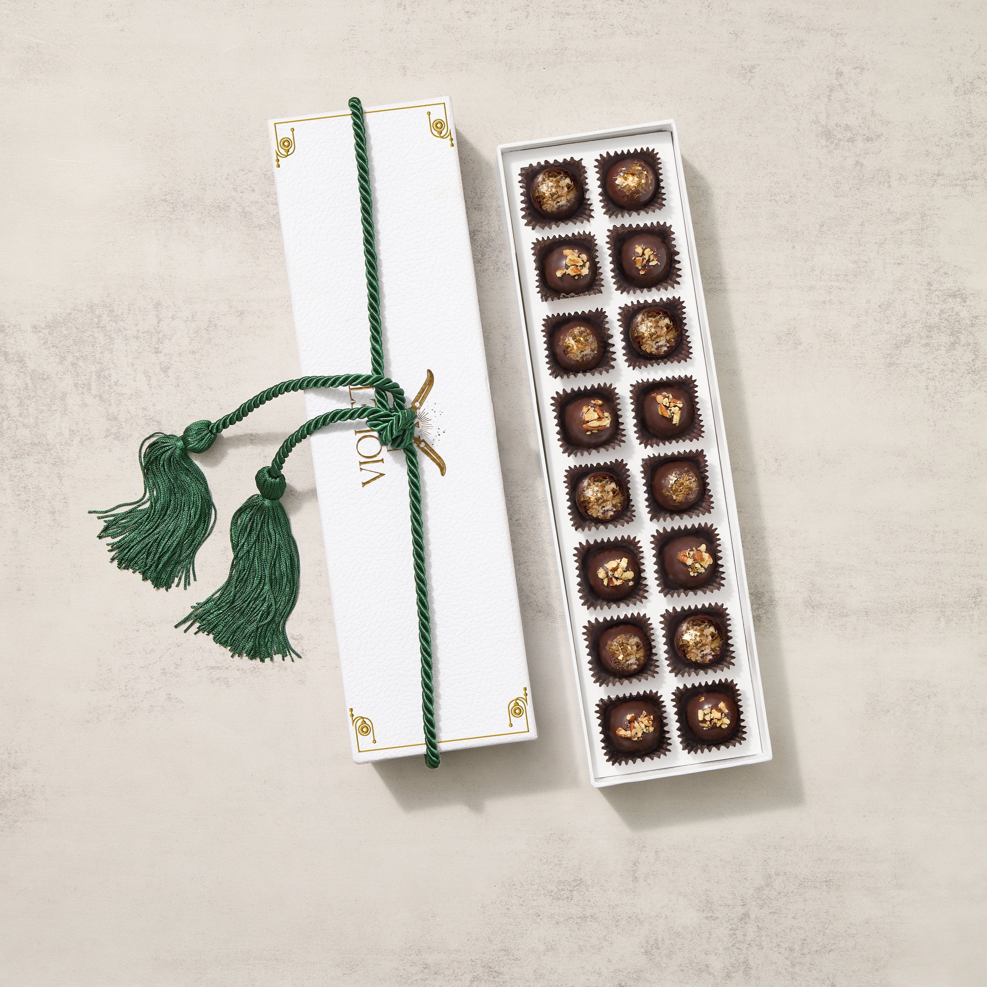 A gift box of chocolate truffles with Lion's Mane White Gold flakes on top, presented with a green tassel.